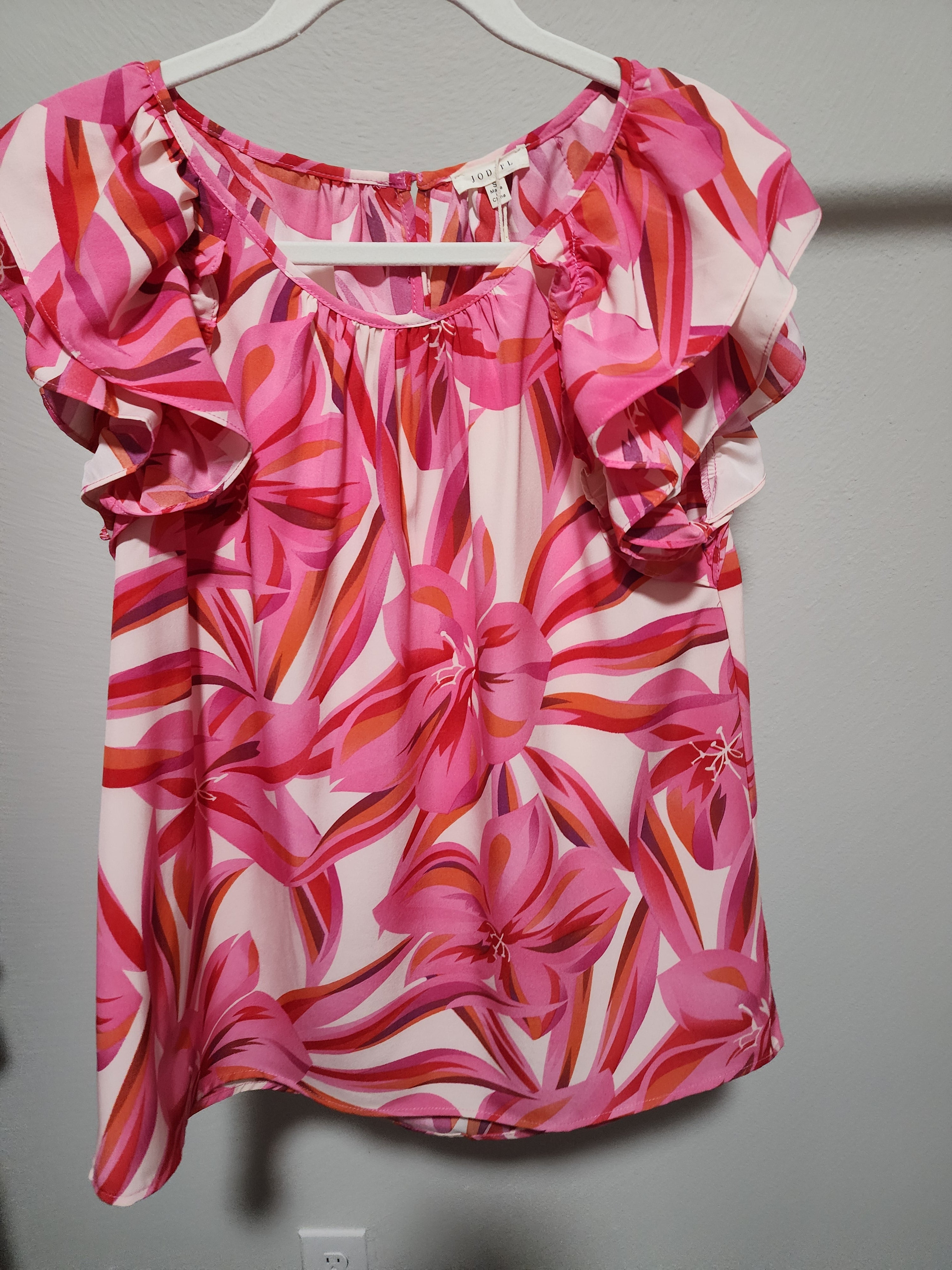- Fuchsia, Red, Orange, Pink and White Floral Double Ruffle Flounce Shoulder Top
- Print top with U-neck featuring wrinkle, back buttoned closure, layer flounce shoulder, and curved hemline.
- Non-sheer, lightweight.