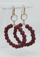 Wine-colored glass beaded circle drop earrings with gold-colored clasps.

Approximate Length: 2.25"
