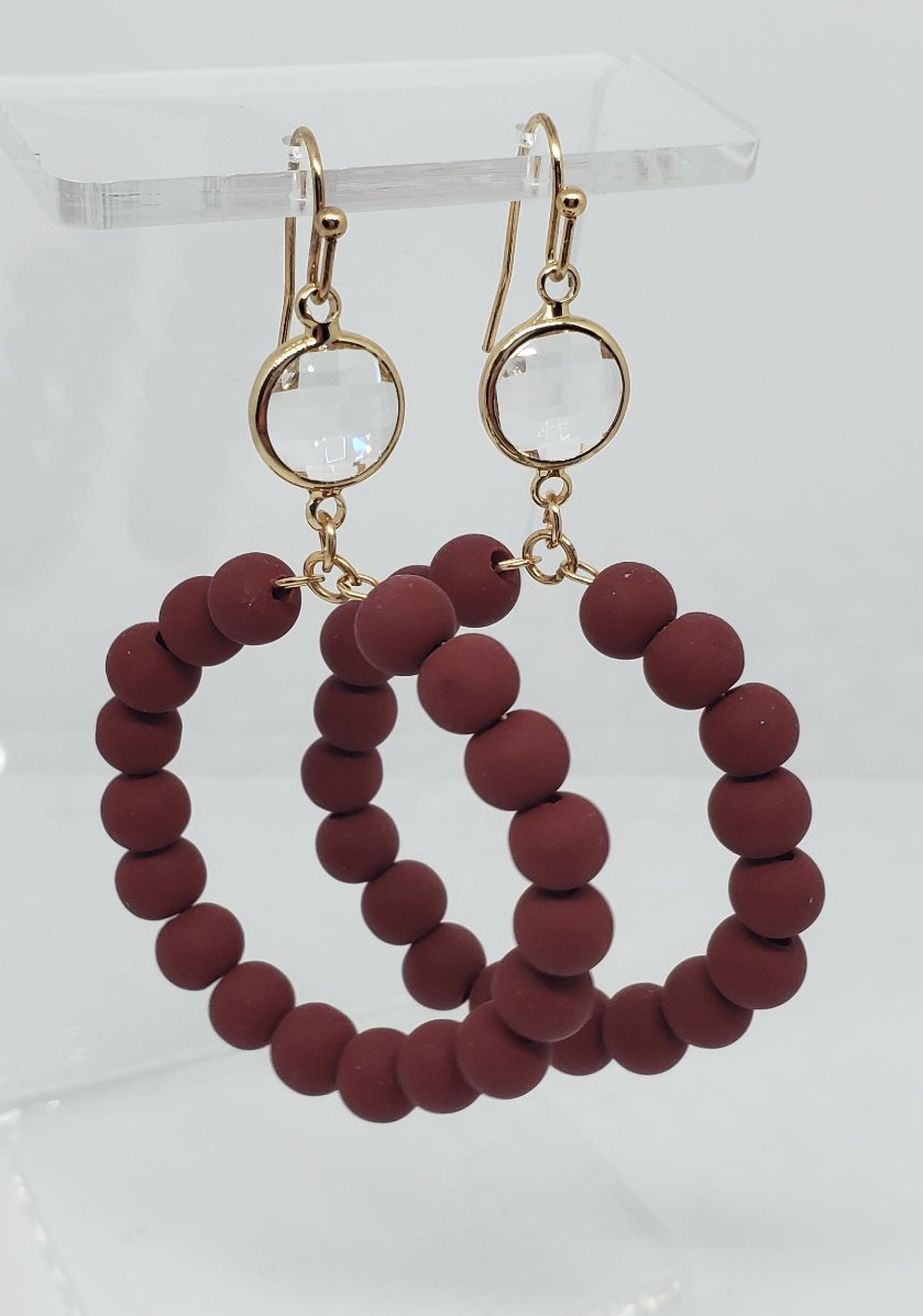 Wine-colored glass beaded circle drop earrings with gold-colored clasps.

Approximate Length: 2.25"