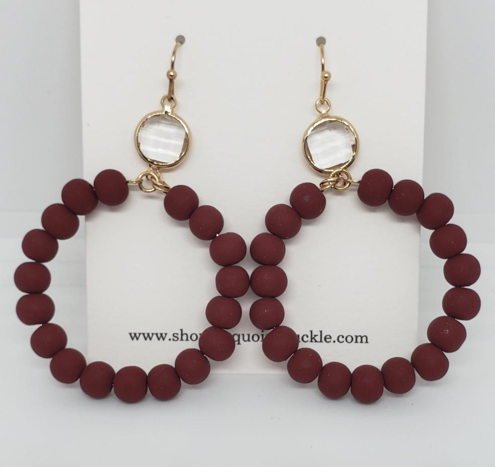 Wine-colored glass beaded circle drop earrings with gold-colored clasps.

Approximate Length: 2.25"