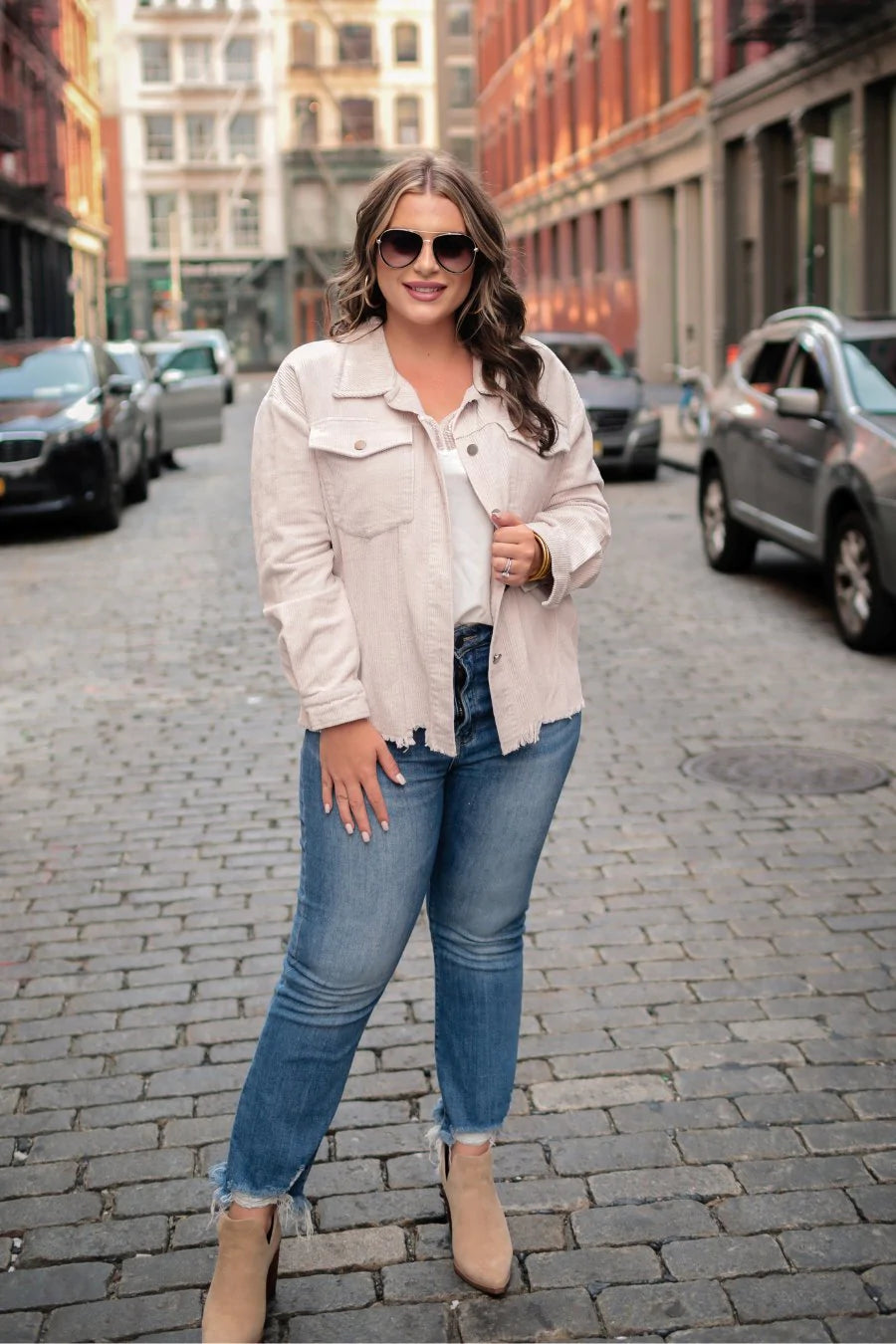 This trendy cream colored corduroy jacket features two button down chest pockets and a raw frayed hemline. 
